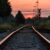 A photo taken low to the ground of railway tracks under a sunset.