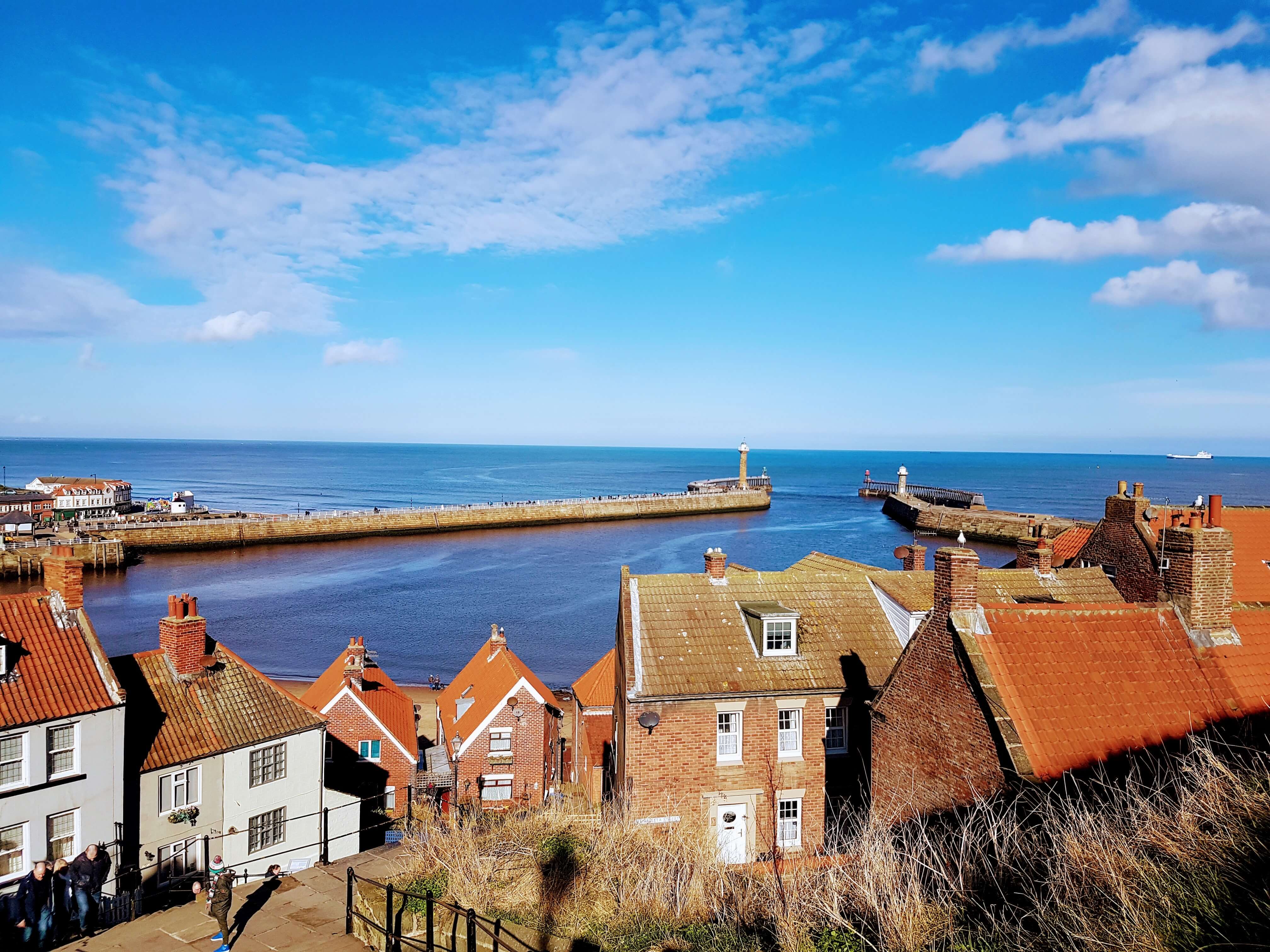 A seaside in Whitby, with houses looking out over a patch of very blue sea.