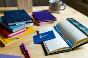 Photo of desk with notebooks and Hey Me business cards.