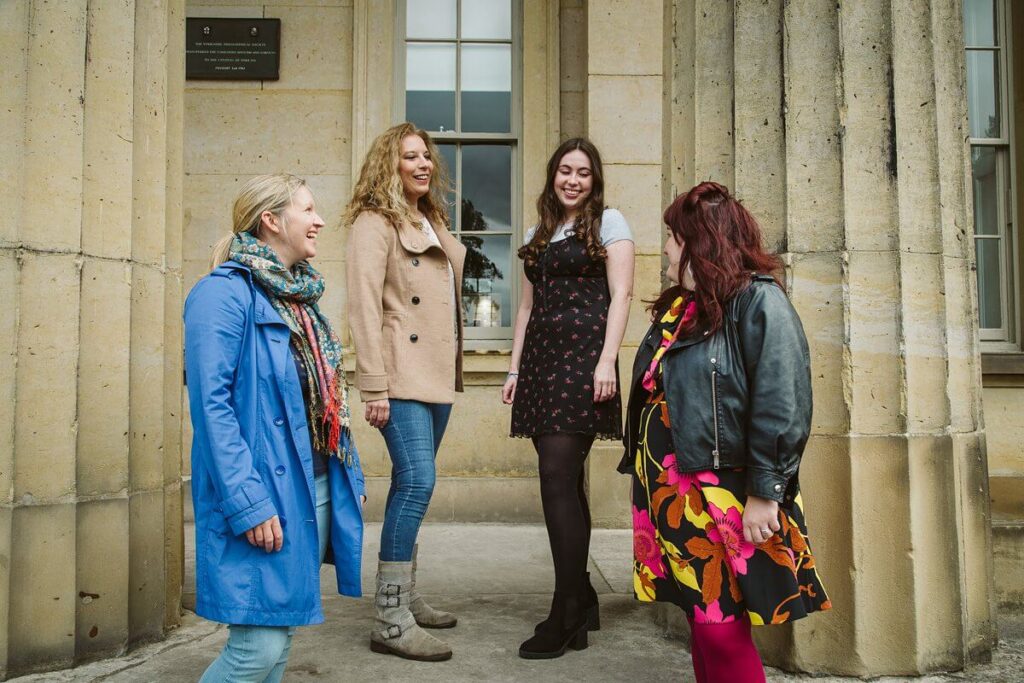 Members of the Hey Me Team, Katie, Gemma, Amelia and Emma (left to right), stand together in conversation.